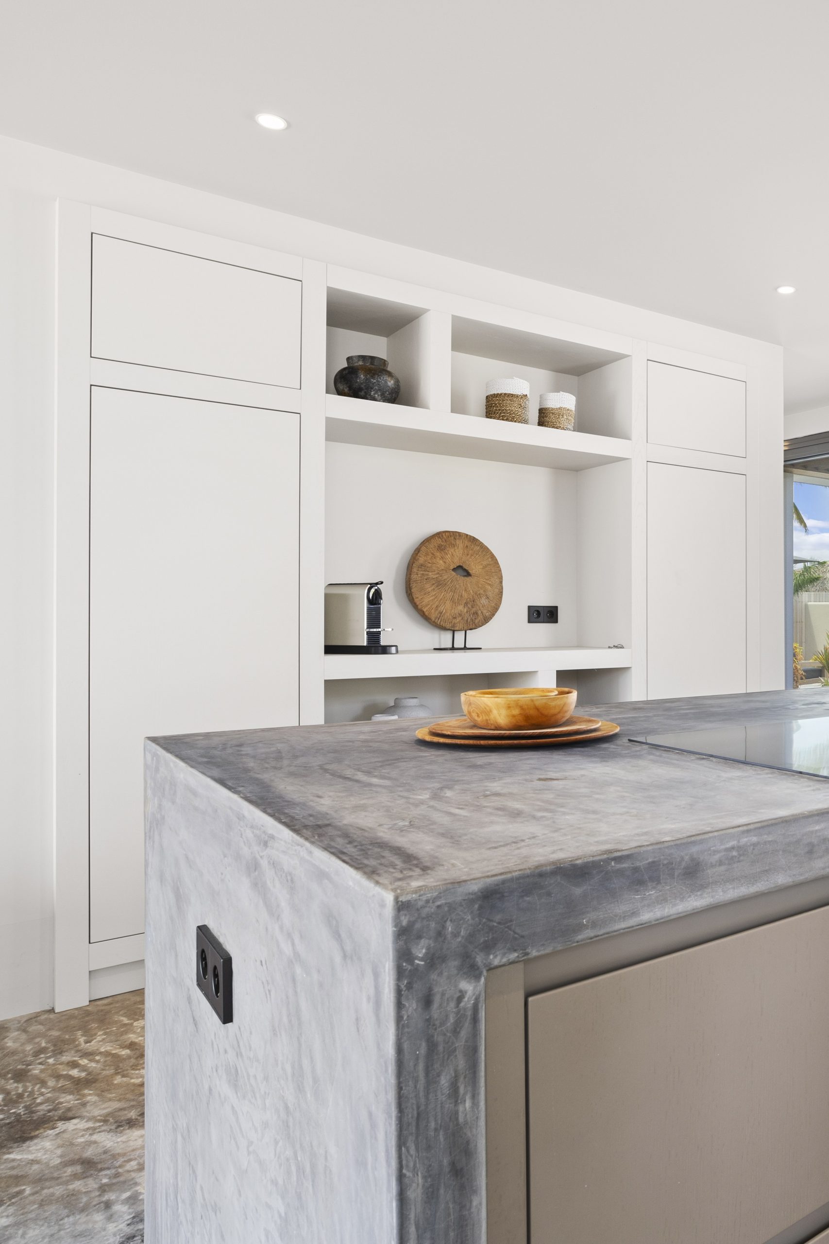 Maatwerkkeuken met betonlook kookeiland en witte kastenwand in Villa Bonaire.
