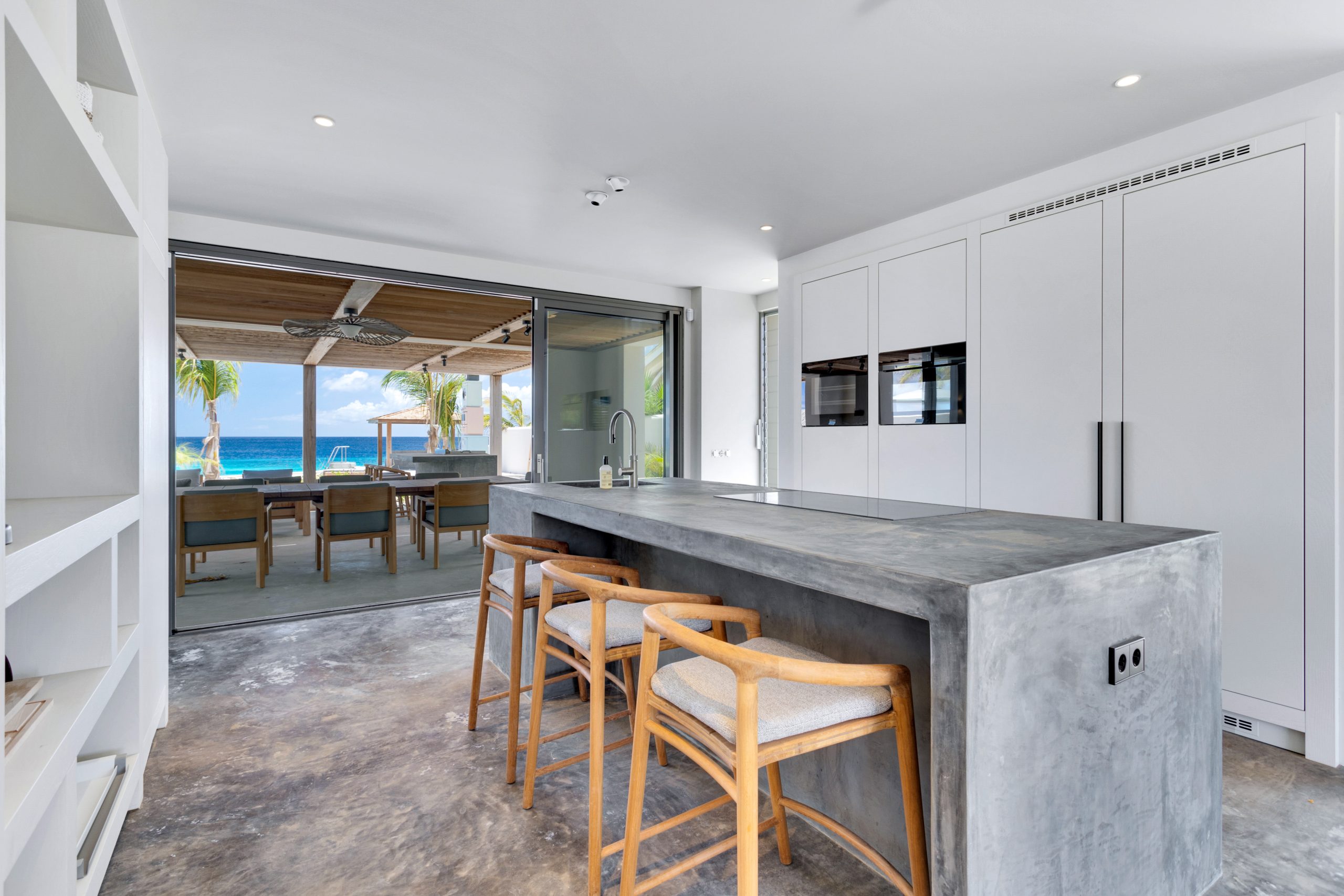 Maatwerkkeuken met betonlook kookeiland en kastenwand in Villa Bonaire.