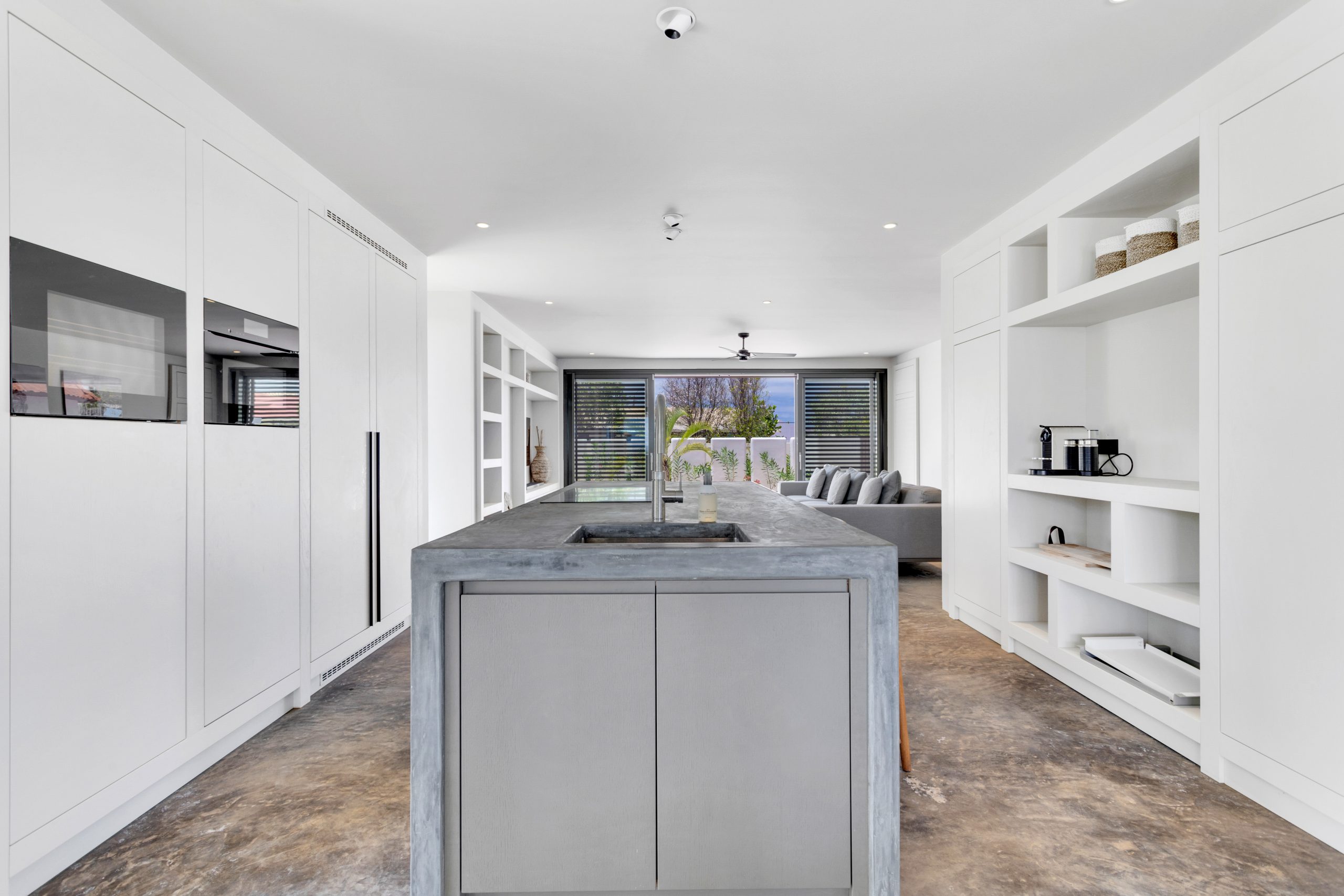 Maatwerkkeuken met betonlook kookeiland en witte kastenwand in Villa Bonaire.