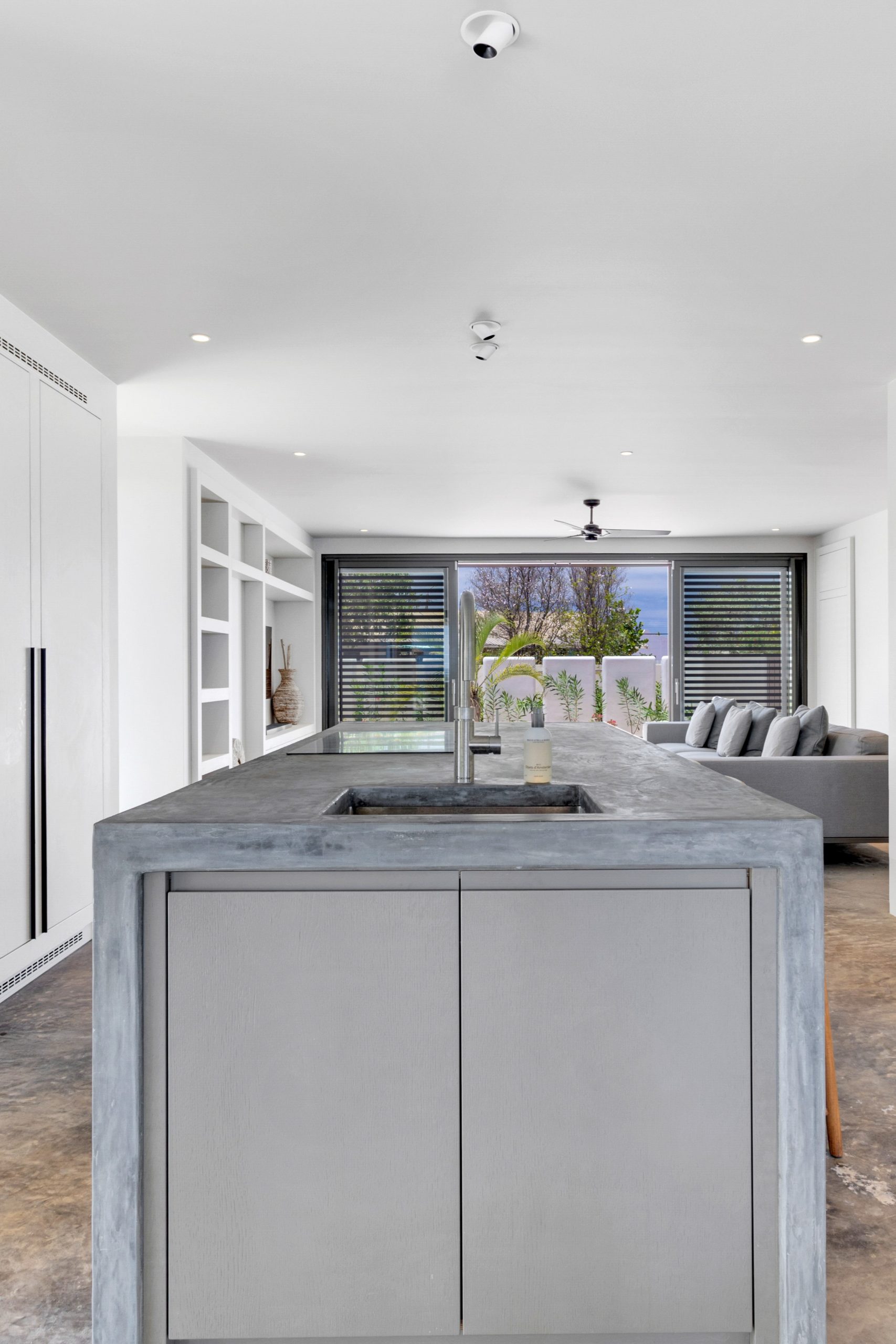 Maatwerkkeuken met betonlook kookeiland en witte kastenwand in Villa Bonaire.