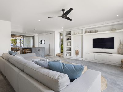 Woonkamer met maatwerk tv-meubel en maatwerkkeuken met betonlook kookeiland in Villa Bonaire.